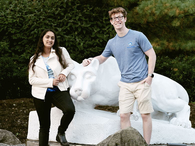 A male student and a female student pose in front of the Lion Shrine on Penn State Behrend campus